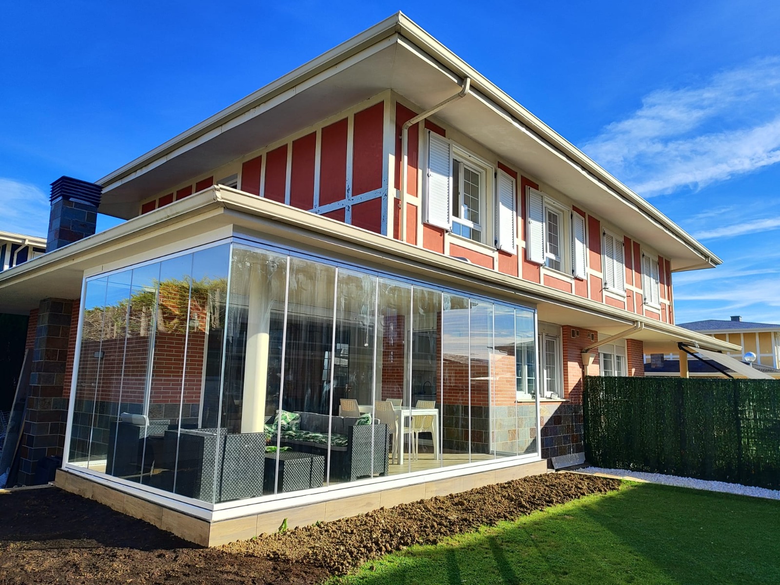 Porche cerrado con cortinas de cristal en una vivienda con jardín